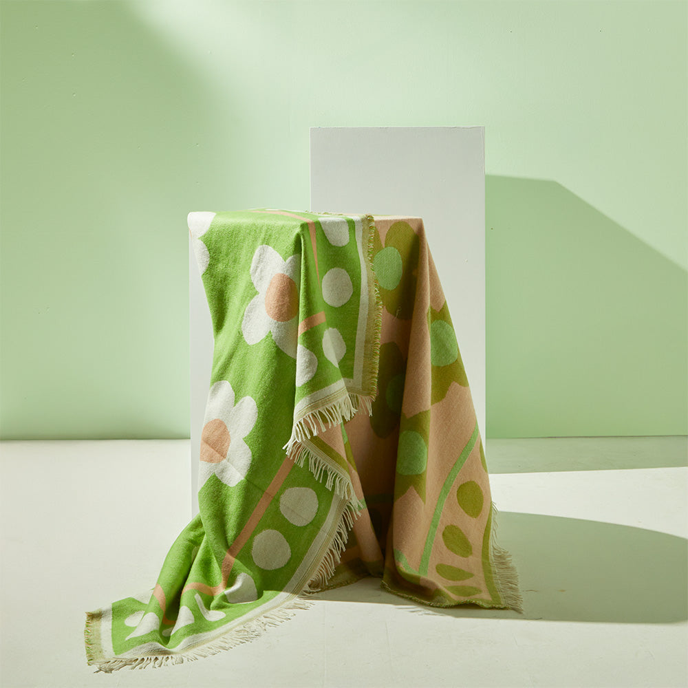 Lush green Nina Throw draped over a sofa, showcasing its elegant texture and size
