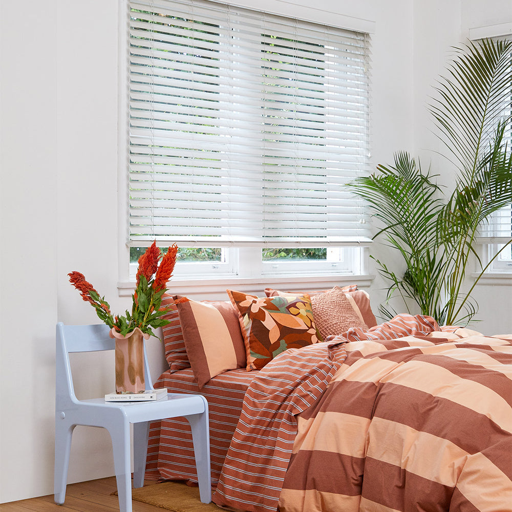 Rust-colored Breeze Quilt Cover Set with bold stripes on a bed